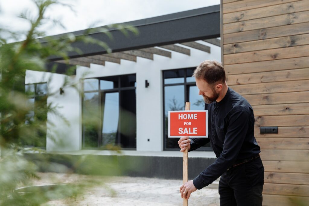 A-man-in-black-long-sleeves-putting-the-signage-outside-a-house