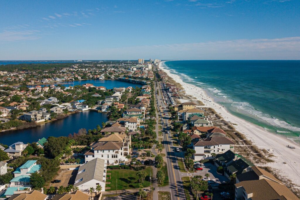 Aerial-view-of-houses-near-a-beach-under-blue-sky