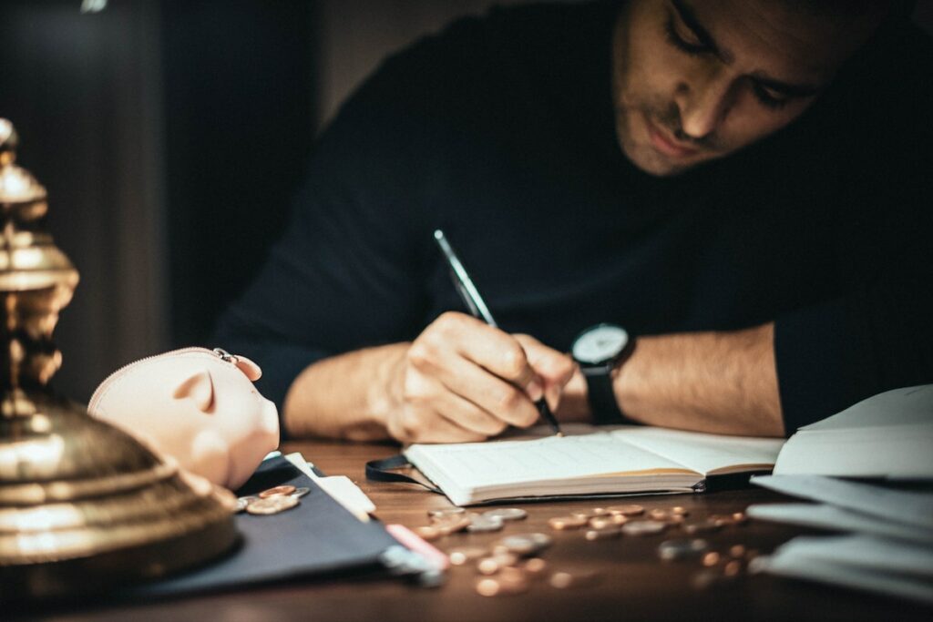 Focused-man-writing-in-account-book-at-table