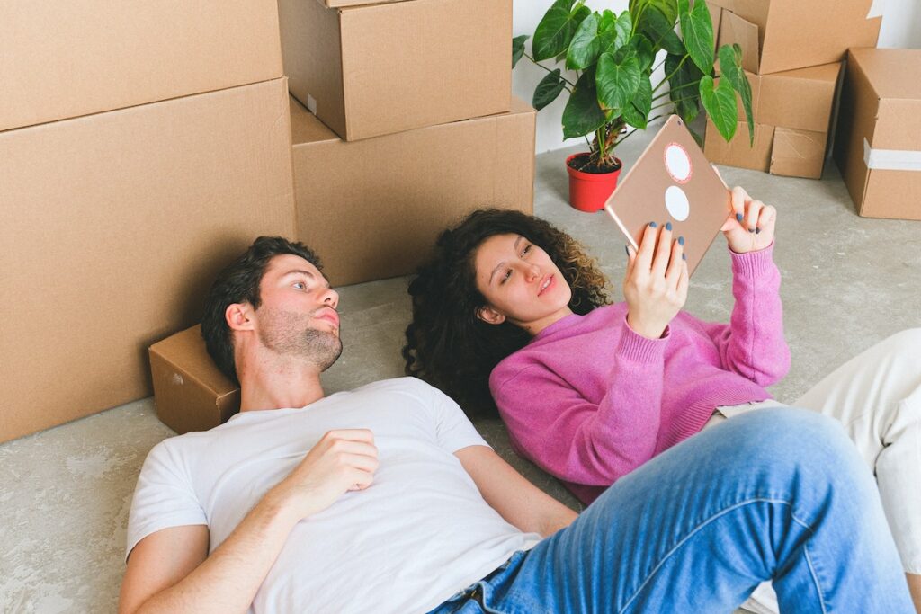 Loving-young-couple-lying-on-floor-and-looking-at-framed-photo-after-relocation